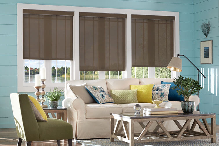 A blue and white living room with brown shades covering the windows half-way.