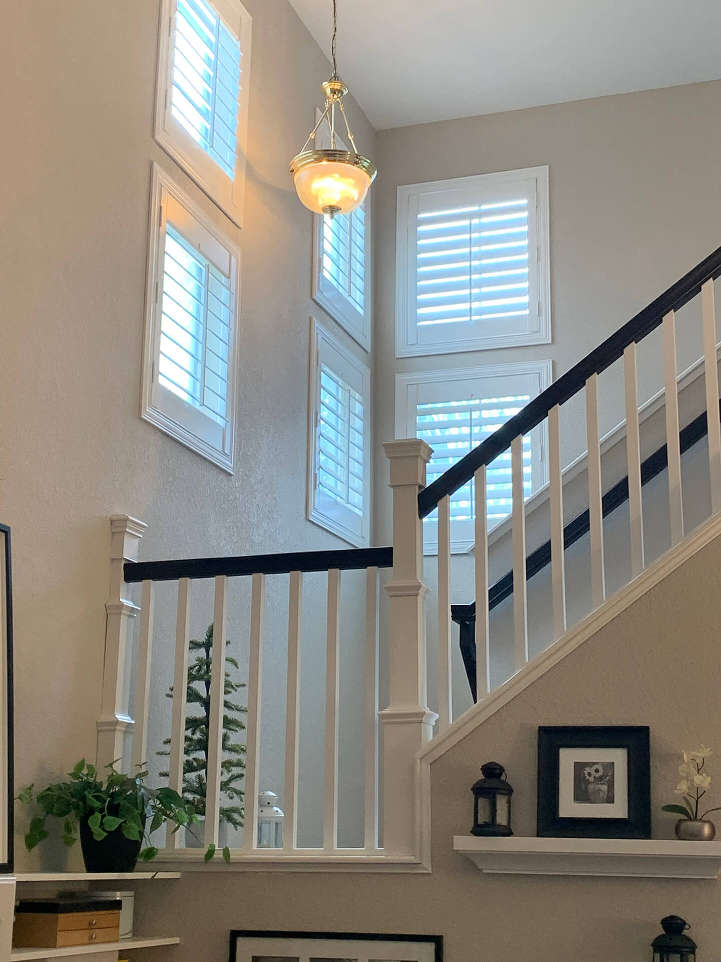 A stairway with high windows covered with shutters.